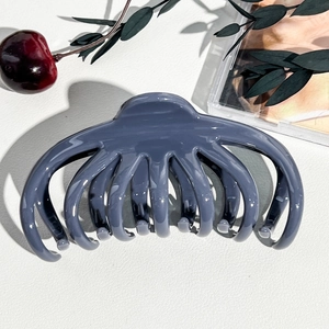 Primo piano di una grande molletta per capelli blu-grigio su sfondo di pelle bianca