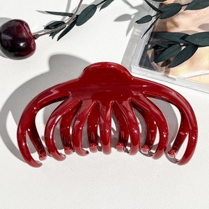 Dettaglio di una molletta per capelli a zucca rosso scuro lucido per capelli folti