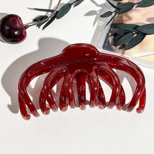 Dettaglio macro della molletta per capelli rosso ciliegia in resina lucida per capelli folti