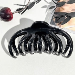 Dettaglio di un fermaglio per capelli a forma di polpo nero lucido su superficie bianca
