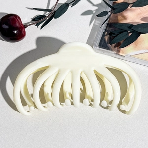 Dettaglio molletta per capelli bianco crema stile polpo su sfondo strutturato pulito