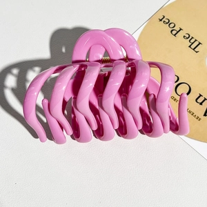 Macro detail of glossy hot pink wave hair claw clip with golden metal spring and smooth finish