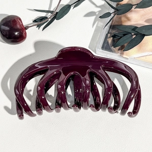 Dettaglio macro della grande pinza per capelli viola scuro con finitura lucida di classe