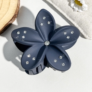 Close-up of matte dark blue plumeria hair claw clip with sparkling rhinestones details