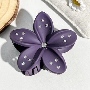Macro detail of purple matte flower hair claw with sparkling rhinestones and sturdy teeth
