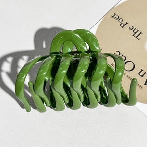 Close-up of a large glossy green pumpkin hair claw clip with strong metal spring