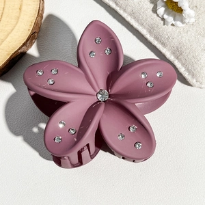 Close-up of matte pink frangipani hair claw clip with sparkling rhinestones details