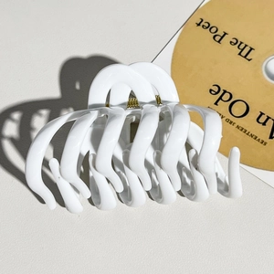 Detail of white glossy pumpkin hair claw clip showing heavy duty metal spring and wavy teeth