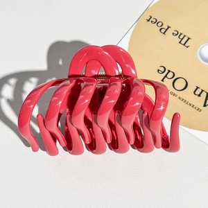 Macro detail of the bright pink pumpkin hair claw clip showing glossy finish and spring