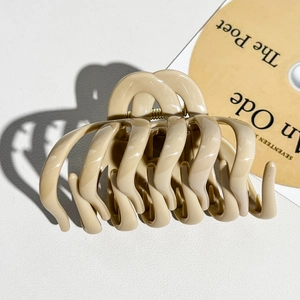 Macro shot of large beige pumpkin claw clip with wave pattern and polished resin finish