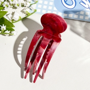 Macro shot of dark red marble textured acetate hair fork with glossy polished finish