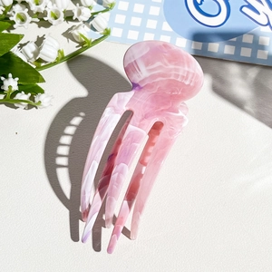 Detailed macro view of pink marble acetate hair pin with four teeth and glossy finish
