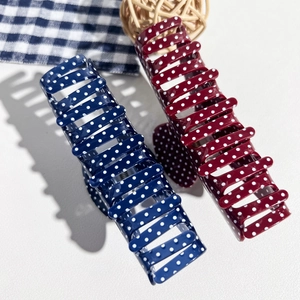 Close-up of navy blue and burgundy polka dot claw clips on a light surface