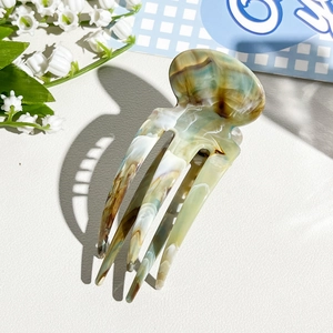 Detailed view of acetate hair fork with vintage green marble texture and long prongs