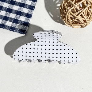 Detailed top view of a classic white polka dot hair claw clip with black spots and teeth