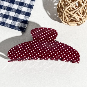 Detail of wine red hair claw clip with white polka dots on smooth resin finish