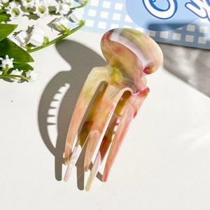 Detail of three-prong marble texture hair fork with pink and green acetate pattern