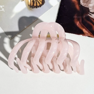 Détail d'une grande pince à cheveux rose pailletée avec une texture transparente