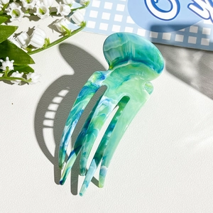 Detail of blue marble marble textured acetate hair claw clip with jellyfish shape design