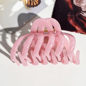 Vue détaillée d'une grande pince à cheveux rose scintillante avec un ressort en métal doré