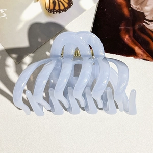 Détail d'une pince à cheveux bleu clair nacré avec ressort doré sur fond de magazine