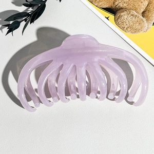 Gros plan d'une grande pince à cheveux pieuvre violette avec paillettes sur fond blanc