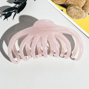 Détail macro d'une pince à cheveux rose pâle scintillante avec design multi-griffes
