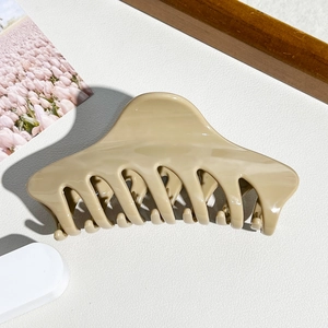 Detailansicht einer minimalistischen cremebraunen Haarklammer auf weißem Hintergrund
