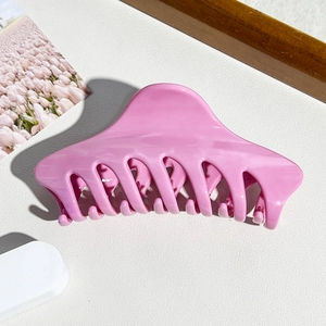 Detailansicht einer glänzenden rosa Haarklammer in Haifischform auf stilvollem Hintergrund