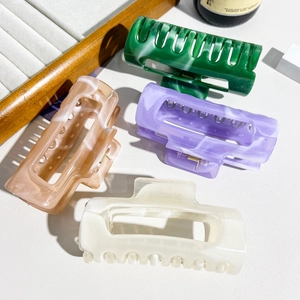 Detail of four marble textured rectangle hair claws in green, purple, pink and cream