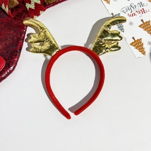 Detail of red velvet headband with golden sequin reindeer antlers and white faux fur balls