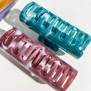 Detail view of large marble texture hair claws in blue and purple acetate finish