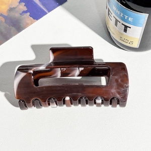 Detailed view of large dark brown tortoiseshell hair claw clip with glossy marble pattern