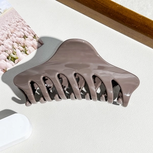Detailansicht der glänzenden dunkelbraunen Haarklammer auf minimalistischem weißem Grund