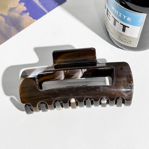 Detailed view of the dark brown marble resin hair claw clip with its sleek rectangular shape