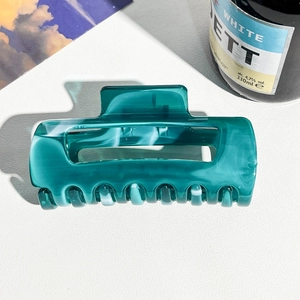 Detailed close-up of dark green marble pattern hair claw clip with acetate texture