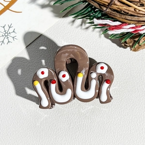 Detail of a brown resin hair claw with white waves and festive red and yellow dots