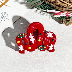 Detailed view of red Christmas hair claw clip with snowflake and wreath patterns