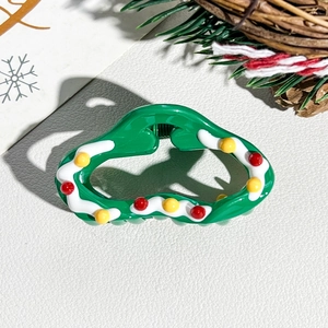 Detail of Christmas green hair claw with white waves and festive red ball ornaments