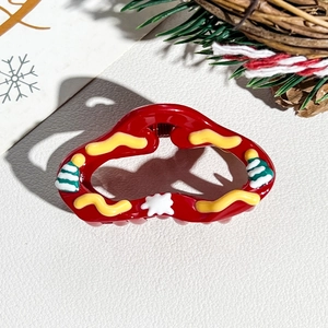 Close-up of a red Christmas wave hair claw with a small tree and snowflake patterns