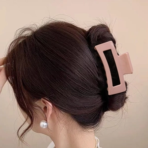 Elegant matte pink rectangular hair claw clip for women styled on a dark brown hair bun