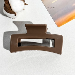 Detail of 8.5cm coffee square hair claw clip on minimalist white leather backdrop