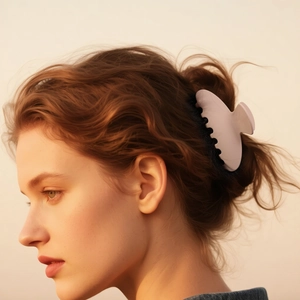 Matte light pink claw clip with rounded edges on wavy dark brown hair for women