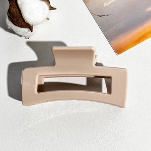 Close-up of 8.5cm square matte beige shark hair claw clip on a stylish textured background