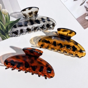 Three leopard print claw clips in grey, honey, and caramel displayed on a white surface