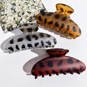 Detailed set of three large leopard print hair claws in amber, grey, and reddish-brown