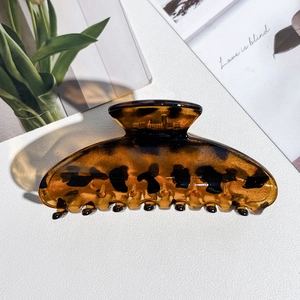 Macro detail of amber leopard print hair claw clip showing a translucent texture and smooth teeth