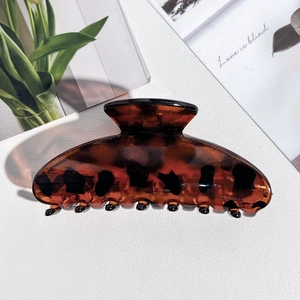 Macro detail of amber resin hair claw clip with leopard print and secure grip teeth