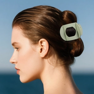 Grande pince à cheveux mate vert clair de forme ovale portée par un mannequin à la plage