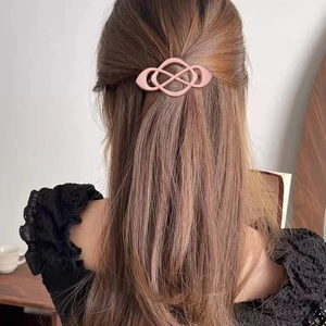 Pink geometric knot hair clip with infinity loop design worn by a female model
